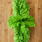 rosette of large green basil leaves that have veining similar to lettuce, on a bamboo cutting board