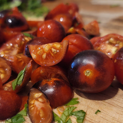 whole and quartered cherry tomatoes on bamboo cutting board